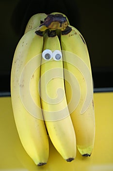 Bananas on a string, yellow background, funny bananas with eyes, background