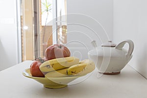 bananas and tomatoes in the fruit bowl. on the kitchen table in the morning