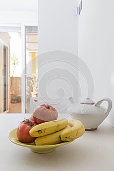 bananas and tomatoes in the fruit bowl. on the kitchen table in the morning