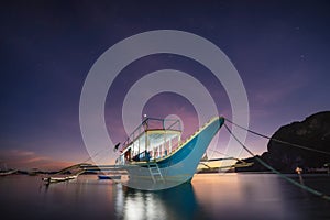 Banca boat at Corong beach illuminated in twilight lit by last sunset light, El Nido, Palawan, Philippines