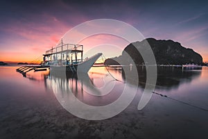 Banca boat at Corong Corong beach on low tide shallow water in twilight lit by sunset light, El Nido, Palawan