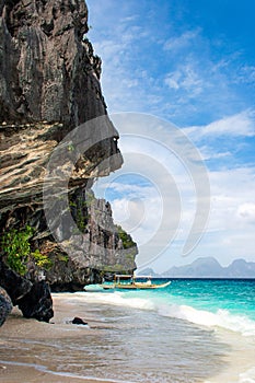 Banca boat on the pristine beach of Entalula island in El nido, region of Palawan in the Philippines. Vertical view