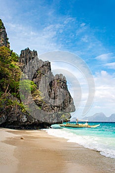 Banca boat on the white sand pristine beach of Entalula island in El nido, region of Palawan in the Philippines. Vertical view