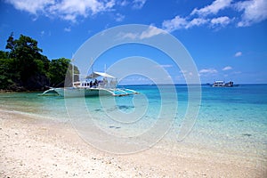 Banca boat on white sand tropical beach on Malapascua island, Philippines photo