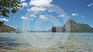 Banca boats floating on water surface with white clouds above. El Nido coastline. Palawan, Philippines