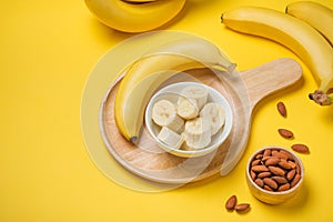 A banch of bananas with almonds on yellow background.