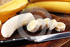 A banch of bananas and a sliced banana over a table.