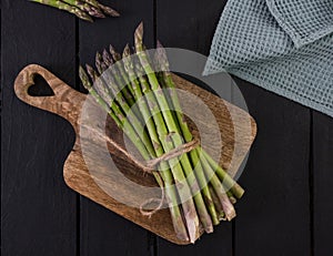 banches of fresh green asparagus on wooden background, top view