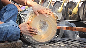 Band of Thai men playing traditional percussion instruments including gongs and a long goat skin drum in a procession leading to a