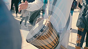 A band in white clothes play drums in the street during the day