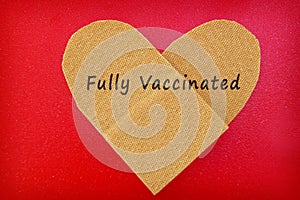 Bandage in a heart shape with Fully Vaccinated text --- COVID-19 vaccine concept