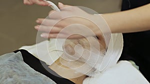 A bandage mask using gauze fabric. Adjustment of gauze tissue around the neck of a girl with cream.