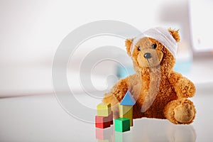 Bandaged Teddy Bear with Block Shapes on the Table