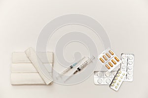 Bandages, syringes, pills, pills and vitamins on a white background, top view. Concept of first aid kit. White