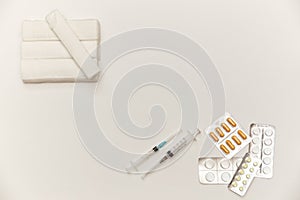 Bandages, syringes, pills, pills and vitamins on a white background, top view. Concept of first aid kit. White