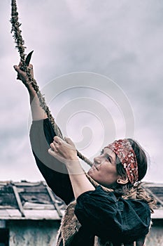 A bandit woman cuts a gallows rope with a knife at a place for execution in a medieval city