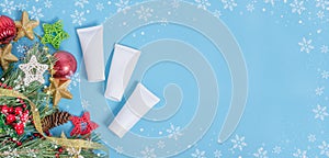 Baner background - Christmas cosmetics sale. Tubes of creams on a blue background with a frame of snowflakes with a copy space