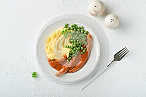 Bangers and mash. Grilled sausages with mash potato and green pea on white plate on light background. Traditional dish of Great