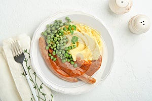 Bangers and mash. Grilled sausages with mash potato and green pea on white plate on light background. Traditional dish of Great