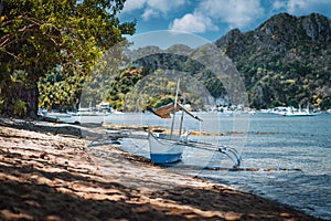 Bangka fishing boat on shore with El Nido village in background, Palawan, Philippines