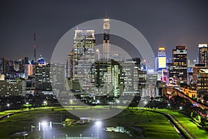 Bangkok business district with the public park area anf the sky train in the foreground at sunset time