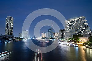 Bangkok cityscape with river and boat at night time