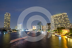 Bangkok cityscape with river and boat at night time