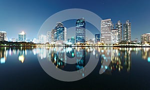 Bangkok night scenery of lakeside skyscrapers reflecting on smooth lake water in beautiful Benjakiti Park