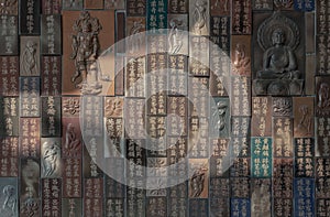 Chinese lettering teachings and Carved buddha images into a slab of colored tiles on temple wall photo