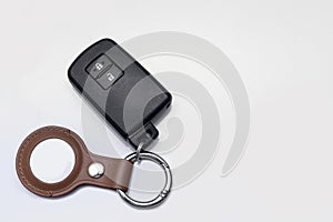 Bangkok, Thailand - April 14, 2023: Modern black remote control of car and Apple Air Tag with brown leather keychain isolated on