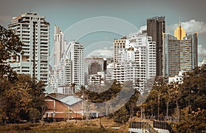 View of Modern high buildings among green trees space in nature against blue sky with clouds at afternoon