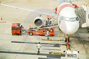 Staff of Thai Air Asia airline using baggage loader cart loading luggage to the airplane