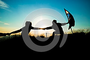 Silhouette of people helping each other hand by hand