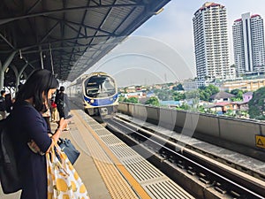 Passengers are waiting the arrival of the airport rail link sky train. People wait in an orderly line behind the yellow arrows poi