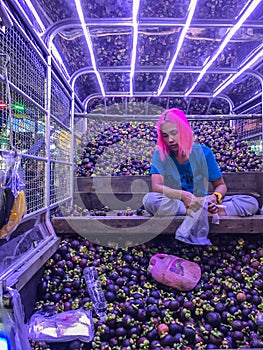 Bangkok, Thailand - July 17, 2017: Asian Woman selling tropical fruit, mangosteens, in the pickup car on the street