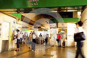 BTS Skytrain in the evening. Nearing Sun Set time. Motion blur of People walking in and out of the station, yellow tones