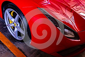 Close-up of Headlights, Wheel, and Rim of Red metallic Ferrari car