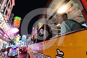 BANGKOK, THAILAND - MARCH 2019: man driving in public bus through China town night market