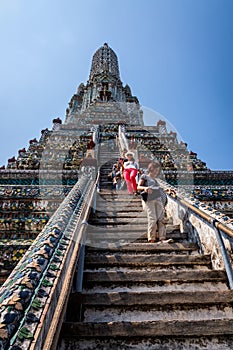 Tourists climbing up and walking down on steep stairs of Wat Arun temple