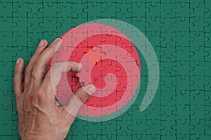 Bangladesh flag is depicted on a puzzle, which the man`s hand completes to fold