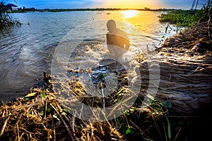 A worker cleans decomposing jute-fibers on the river water in the evening time at Rajrajeshor,