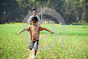 Bangladeshi agricultural fields. Two children are dancing happily on the path. Village: Puijor, City: Rajbari, Bangladesh. Capture