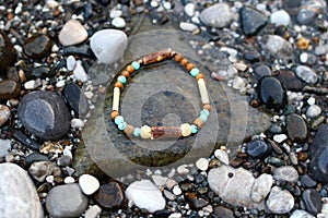 Bangle made from natural wooden materials and minerals on the wet stones near to sea. Handcraft precious item. Jewelry accessories