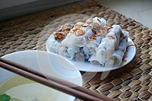 Banh cuon-vietnamese steamed rice rolls with minced meat inside accompanied by bowl of fish sauce.