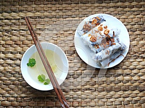 Banh cuon-vietnamese steamed rice rolls with minced meat inside accompanied by bowl of fish sauce.