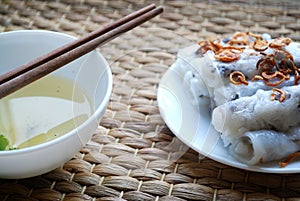 Banh cuon-vietnamese steamed rice rolls with minced meat inside accompanied by bowl of fish sauce.