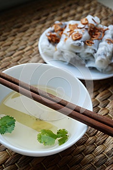 Banh cuon-vietnamese steamed rice rolls with minced meat inside accompanied by bowl of fish sauce.