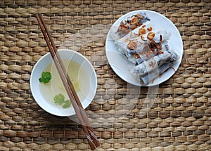 Banh cuon-vietnamese steamed rice rolls with minced meat inside accompanied by bowl of fish sauce.