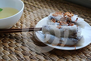 Banh cuon-vietnamese steamed rice rolls with minced meat inside accompanied by bowl of fish sauce.