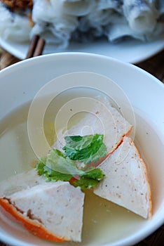 Banh cuon-vietnamese steamed rice rolls with minced meat inside and pieces of vietnamese ham accompanied by bowl of fish sauce.